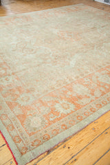 Oushak rug corner showing softened orange border pattern and pomegranate red fringe.
