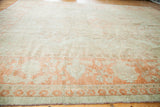 Vintage Oushak carpet border with softened orange and antique ivory patterns, and pomegranate red fringe.