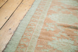 Softened orange and wooded tones in vintage Oushak rug's border.