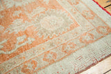 Softened orange and antique ivory border patterns on a hand-knotted Oushak wool rug.