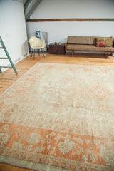 Vintage Oushak carpet's softened orange border and pomegranate red fringe with sprawling designs.