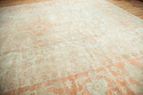 Softened orange curvilinear patterns on an ivory Oushak rug detail.