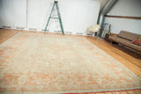 Vintage Oushak carpet, sprawling ivory and softened orange curvilinear design with pomegranate red fringe.