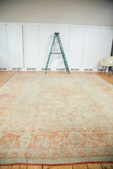 Lower corner of vintage Oushak carpet, showing softened orange design and passionate red fringe.