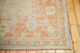 Vintage Oushak carpet corner, ivory floral motifs on softened orange field, subtle red fringe.