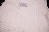 Close-up of white knit cropped top with wavy pattern and delicate perforations.