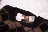 Close-up of Fendi argyle sweater's black ribbed collar showing FF logo and brand tags.