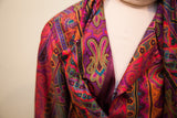 Vibrant psychedelic paisley pattern in magenta, purple, and teal on the 70s dress.
