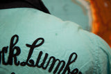 Close-up of vintage turquoise bowling shirt back, black 'rk Lumbe' embroidery, faint stain.