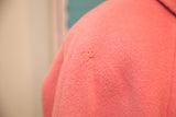 A small moth nibble imperfection on the vintage pink wool coat fabric.