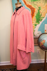 Profile view of the vintage pink wool coat, highlighting its loose sleeve, pocket, and purple trim.