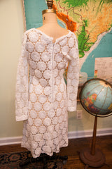 Back of vintage 60s white crocheted lace dress, showcasing zipper and daisy pattern.