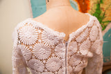 Back of vintage 60s white crocheted lace dress, showing zipper and intricate floral pattern.
