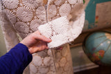 Vintage 60s white crocheted lace dress cuff with intricate floral pattern and slight fraying.