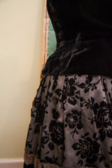 Luxurious black velvet top above pleated skirt with rose pattern and fringe detail.