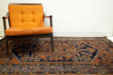Warm earthy rust and deep navy tribal patterns on a vintage area rug edge.