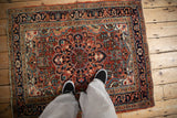 Standing view of a vintage Heriz rug with a saturated brick red and sapphire blue scalloped medallion.