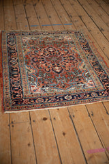 Angled view of a vintage Heriz rug showing its brick red field and navy scalloped medallion.