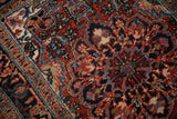 Detailed view of the hand-knotted pile showing saturated brick red and blue floral motifs.
