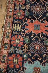 Antique Senneh rug's navy field with vibrant Harshang palmettes and a worn border detail.