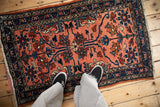 A person's view down at the floral patterns of a vintage Persian Lilihan rug.