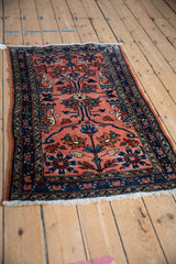Angled perspective of a vintage Lilihan rug with scrolling blossoms and a dark navy border.