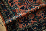 A fold in the vintage Lilihan rug showing its plush pile and scrolling floral pattern.