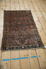 Intricate dusty rose and navy floral pattern on vintage Persian Lilihan rug corner.