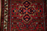 Vintage Hamadan rug close-up: ruby red field, sapphire blue Herati motifs and ivory border.