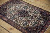 A vintage Persian Senneh rug mat shown at an angle, highlighting its navy hexagonal medallion.