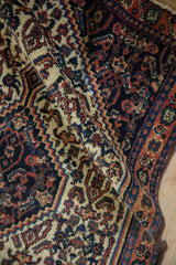 Folded view of a vintage Senneh rug showing the detailed Herati motif and short, dense pile.