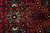 Fine weave and ruby red ground of vintage Sarouk rug with blue, yellow, green floral motifs.