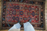 The dense pile and geometric floral columns of an antique Kurdish Bijar rug seen from above.