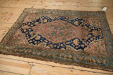 Malayer rug's aged corner reveals tattered ends and dusty green botanical borders.