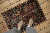Intricate floral blossoms in dusty blush, navy, and powder blue on a vintage Lilihan rug corner.