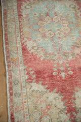 Distressed Oushak rug's worn border and field detail with raspberry red and sea foam green.