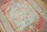 Textured distressed Oushak rug with raspberry, sea foam, and beige motifs, displaying wear to knot heads.
