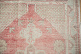 Corner spandrel's fine lattice detail on a distressed Oushak rug in dusty cherry red and pale slate blue.