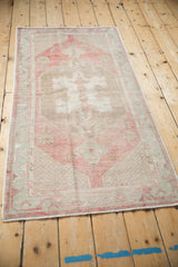 Vintage distressed Oushak runner viewed from an angle, highlighting its faded red and coffee brown hues.