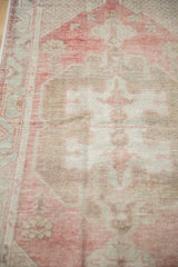 Time-softened pile of a distressed Oushak runner showing hand-knotted texture and lattice detail.
