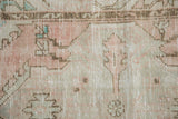 Distressed Oushak rug pile texture showing faded dusty rose, pale turquoise, and ivory.