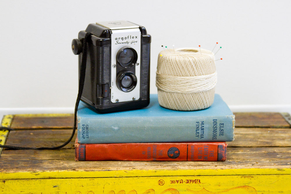 Vintage spool of ecru-colored crochet thread with colorful sewing pins in the top.
