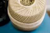 Close-up of the neat, crisscross pattern on a spool of vintage ecru thread.