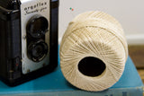 The radial pattern of tightly wound antiqued ivory thread on a vintage spool.