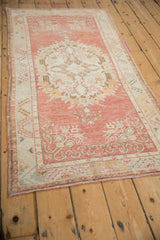 Vintage distressed Oushak runner detail: faded cherry red, ivory, and soft brown floral motifs.