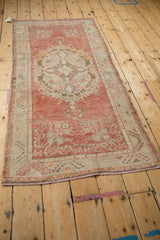 Corner detail of distressed Oushak runner, faded cherry red field, ivory border, coffee brown cloudband motifs, visible wear.
