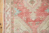 Distressed Oushak rug pile with visible wear, featuring faded cherry red and turquoise tones.