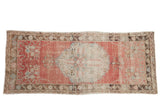 Distressed Oushak runner featuring a large medallion in soft blush pink, ivory, and coffee brown.