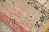 Corner detail of a distressed Oushak rug's low pile texture, in blush pink with a coffee brown border.