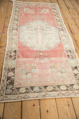 Angled perspective of a vintage Oushak runner showing its length, distressed texture, and soft pink color.